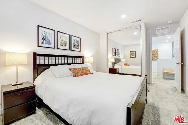 a spacious bedroom with a bed and a lamp
