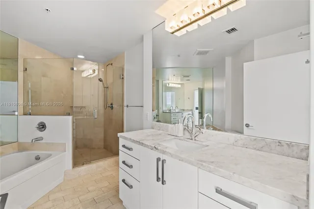 a bathroom with a granite countertop sink a mirror a bathtub and shower