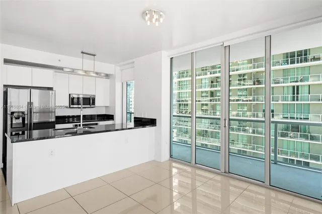 a large kitchen with kitchen island a large window and stainless steel appliances