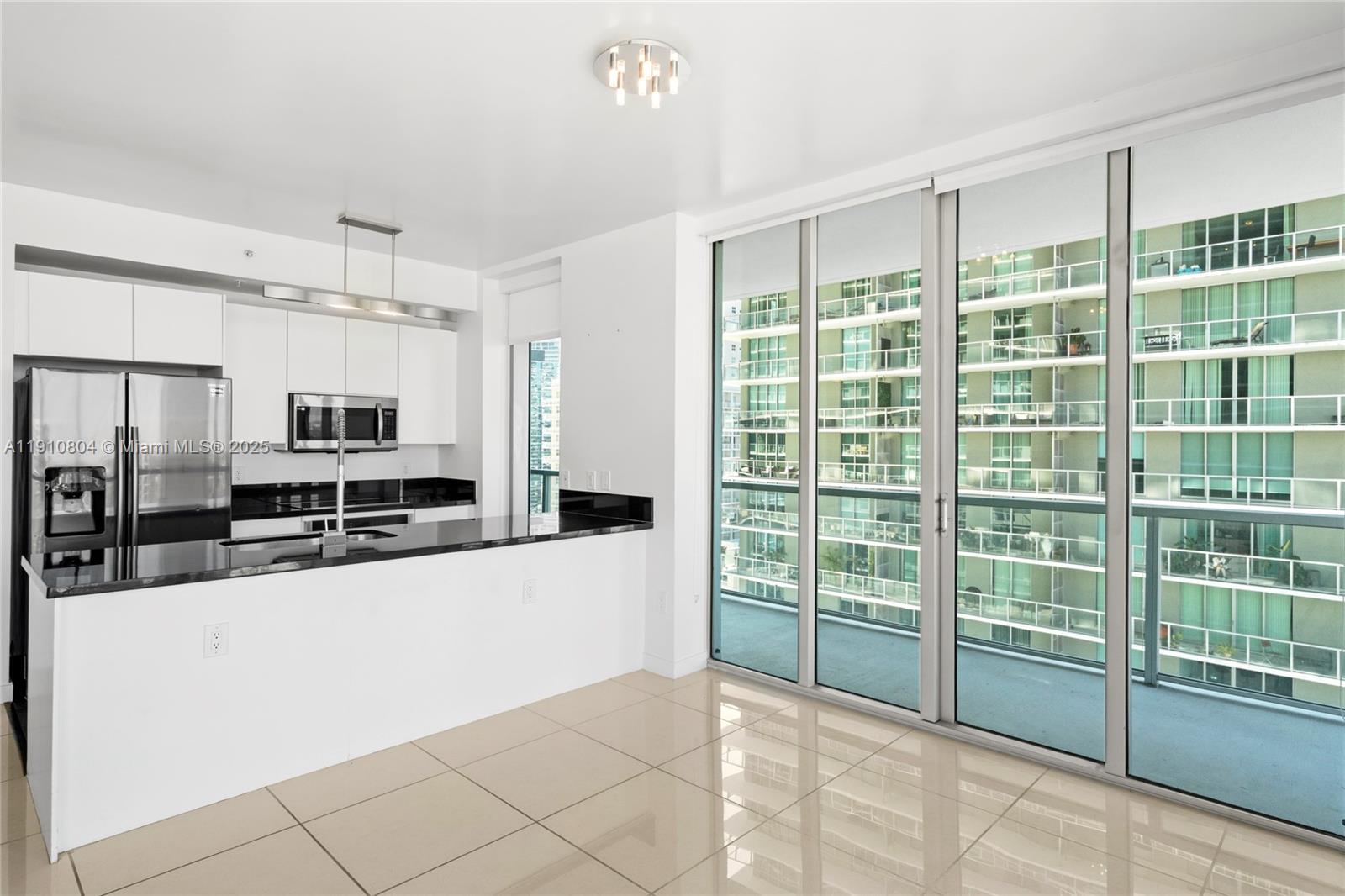 1111 Southwest 1st Avenue, Unit 2414N Miami, FL 33130 - Photo 8 of 49 a large kitchen with kitchen island a large window and stainless steel appliances