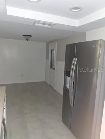 a view of a refrigerator in kitchen and an empty room