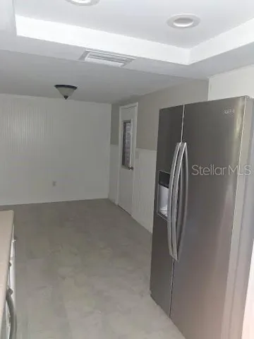 a view of a refrigerator in kitchen and an empty room