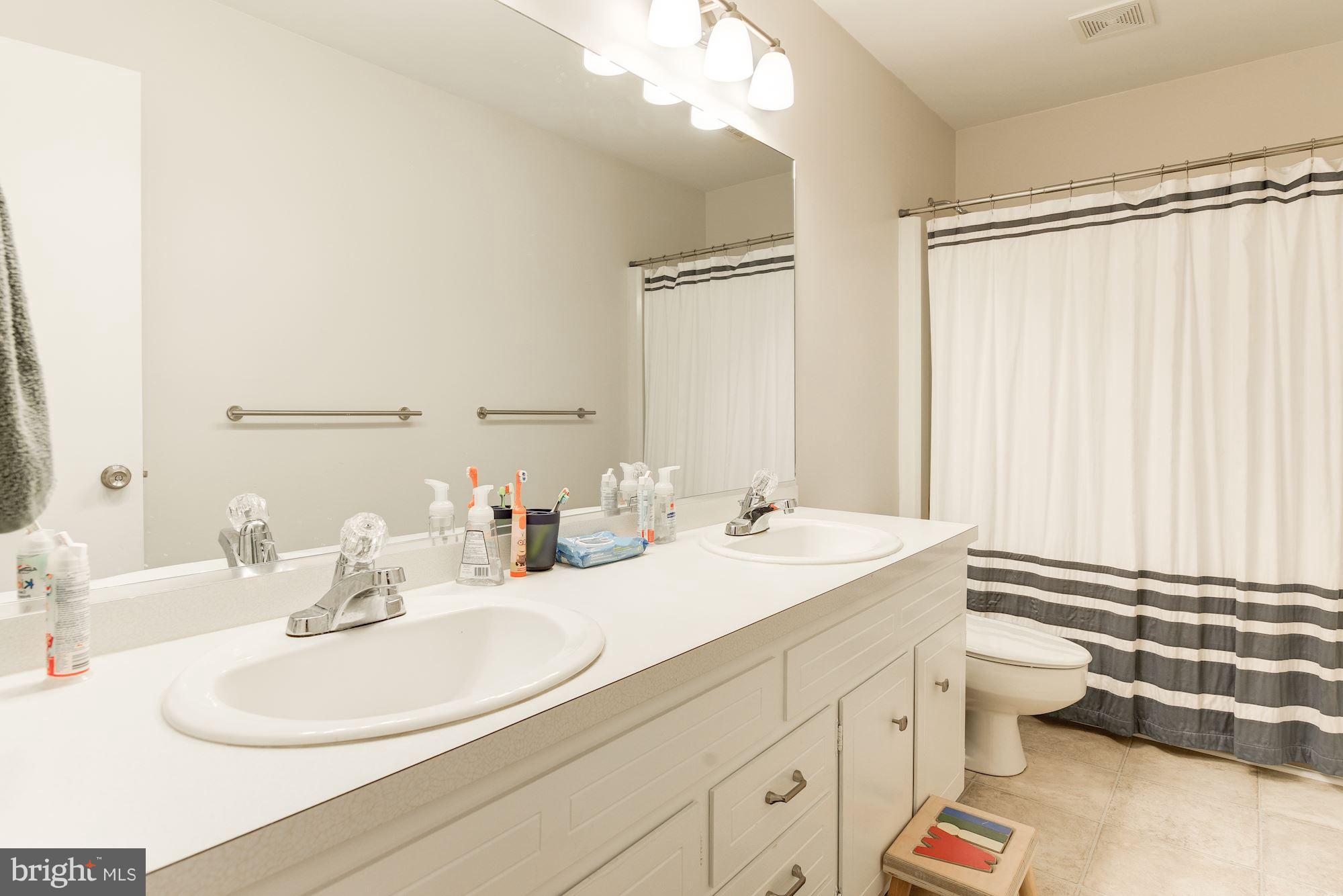 7608 Hamilton Spring Road Bethesda, MD 20817 - Photo 14 of 21 a bathroom with a double vanity sink toilet and a mirror