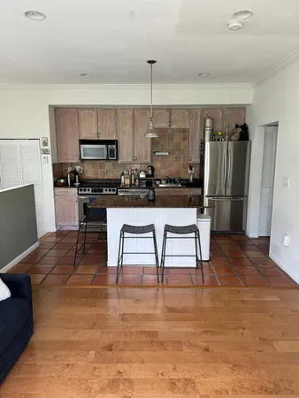 a kitchen with stainless steel appliances kitchen island granite countertop a refrigerator a stove a sink a dining table and chairs with wooden floor