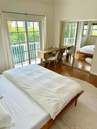 a bedroom with a bed a table and large windows