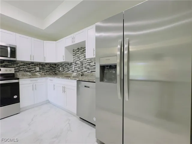 a kitchen with a refrigerator and white cabinets