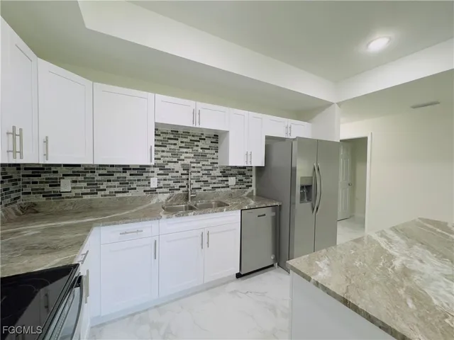 a kitchen with stainless steel appliances granite countertop a sink and refrigerator