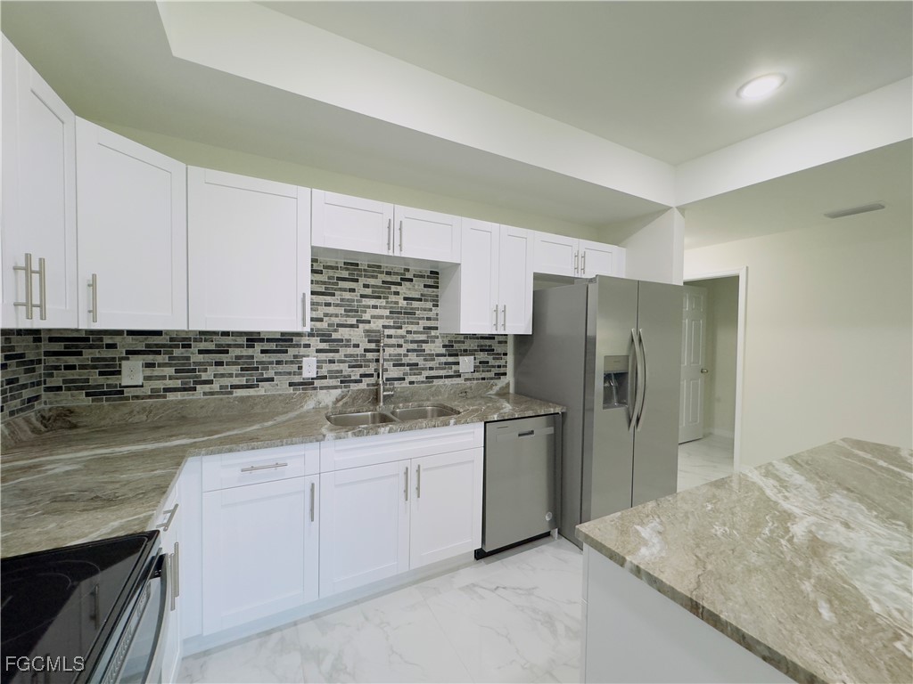 884 Alabama Road South Lehigh Acres, FL 33974 - Photo 12 of 37 a kitchen with stainless steel appliances granite countertop a sink and refrigerator