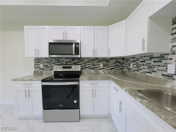 a kitchen with granite countertop a stove sink and microwave
