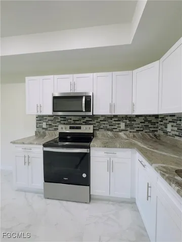 a kitchen with granite countertop white cabinets and stainless steel appliances