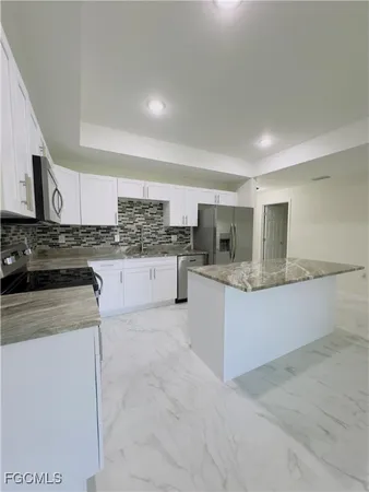 a large kitchen with granite countertop a stove a sink a refrigerator a dining table and chairs