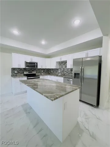 a large kitchen with granite countertop a sink and stainless steel appliances