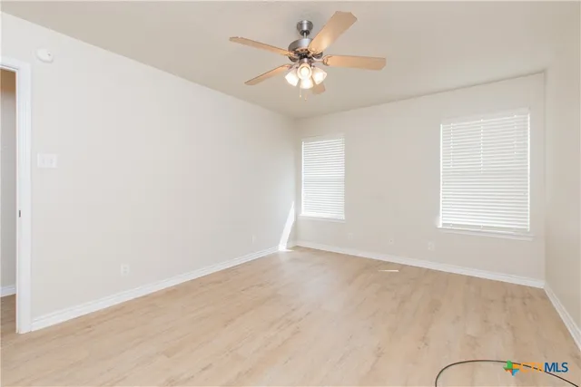 an empty room with a chandelier fan and windows
