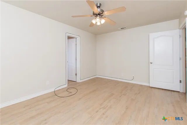 an empty room with wooden floor and ceiling fan