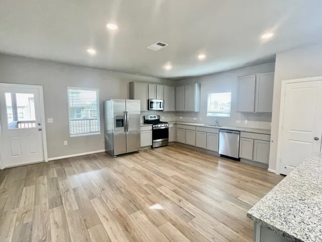a kitchen with stainless steel appliances granite countertop a refrigerator and a stove top oven