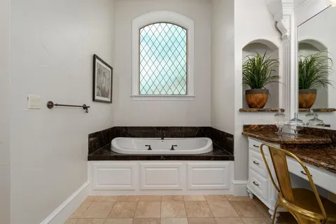 a bathroom with a tub a sink and mirror