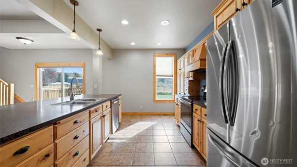 a kitchen with stainless steel appliances granite countertop a refrigerator a stove and a sink with wooden floor