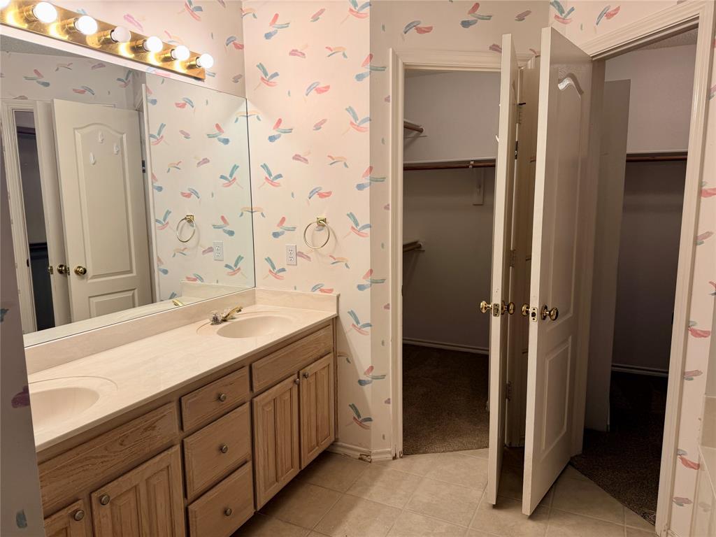 7632 Arbor Ridge Court Fort Worth, TX 76112 - Photo 9 of 19 a bathroom with a double vanity sink a mirror and a shower