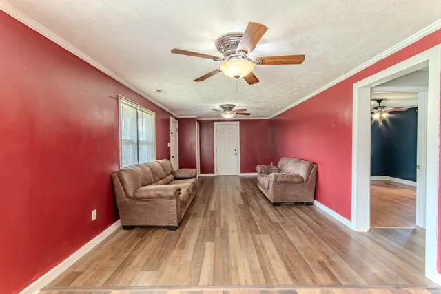 a view of a hallway with wooden floor and a bathroom