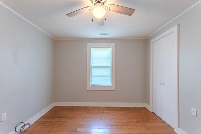 an empty room with wooden floor and cabinet