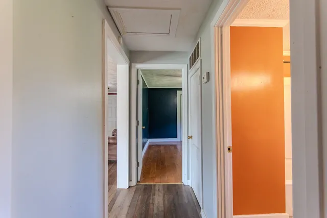 a view of a hallway with wooden floor and a door