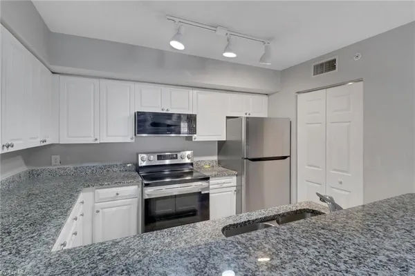 a kitchen with granite countertop a refrigerator stove and microwave