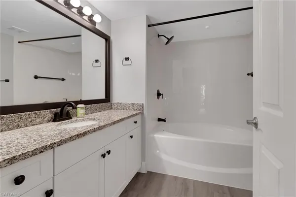 a bathroom with a granite countertop sink mirror and a bathtub