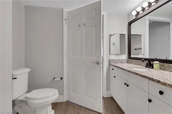 a bathroom with a granite countertop sink a toilet and a mirror