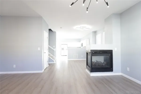 a view of a kitchen and an empty room with wooden floor