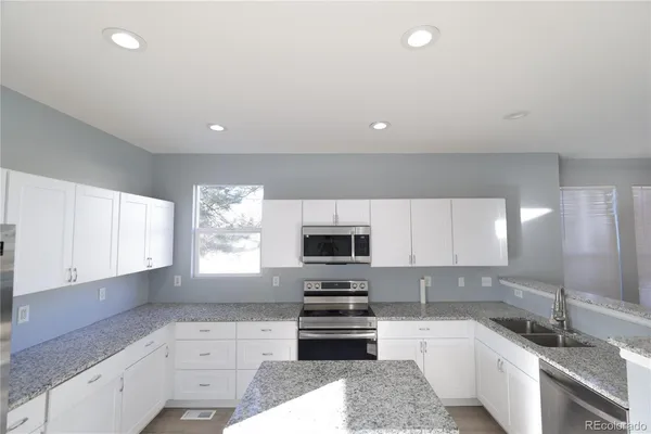 a kitchen with granite countertop a stove sink and microwave