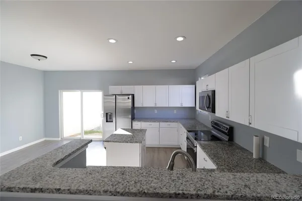 a kitchen with stainless steel appliances granite countertop a sink a stove top oven a counter space and cabinets