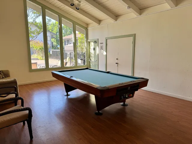 a room with pool table windows and wooden floor
