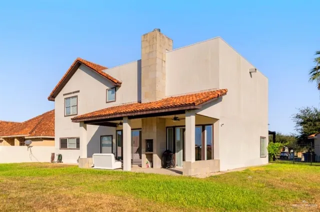 a view of a house with a yard potted plants and a chair