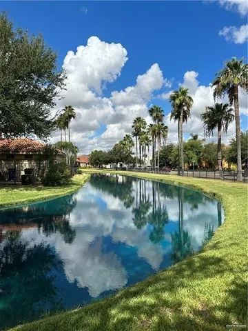 a view of a lake with a yard and large trees