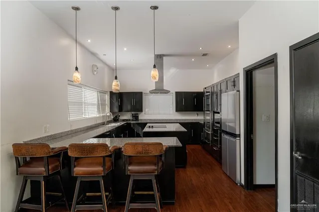 a kitchen with stainless steel appliances kitchen island granite countertop a table chairs and a refrigerator