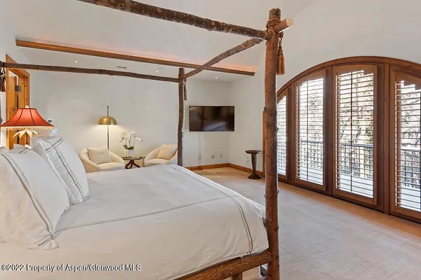 a bedroom with a bed a flat screen tv and a window