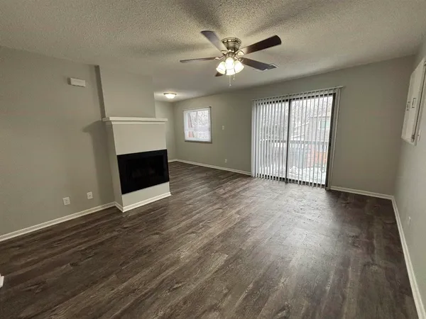 an empty room with wooden floor chandelier fan and windows