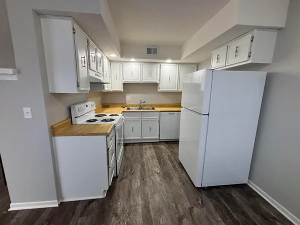 a kitchen with a refrigerator a sink and wooden floor
