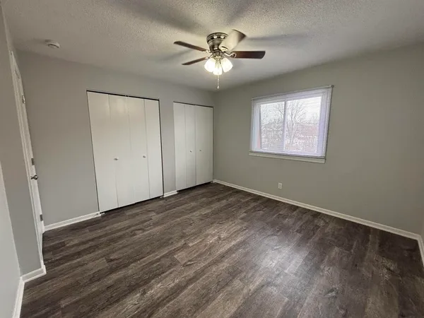 an empty room with wooden floor and ceiling fan