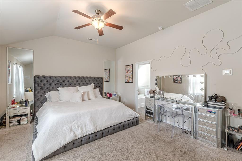 7425 Faith Street Fairburn, GA 30213 - Photo 21 of 29 a bedroom with a bed a chandelier and dresser