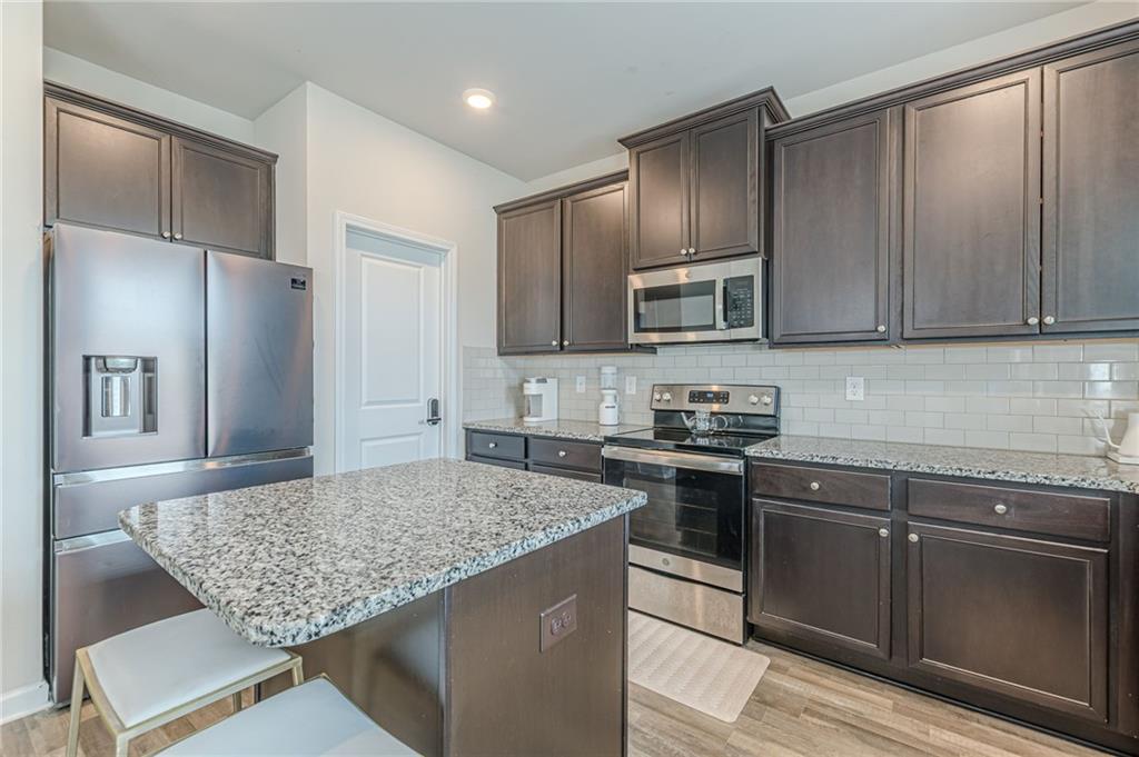 7425 Faith Street Fairburn, GA 30213 - Photo 10 of 29 a kitchen with granite countertop wooden cabinets and stainless steel appliances