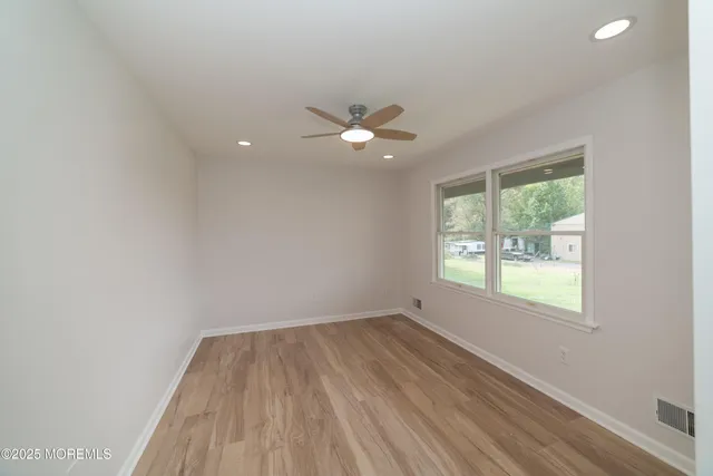 a view of an empty room with a window and wooden floor