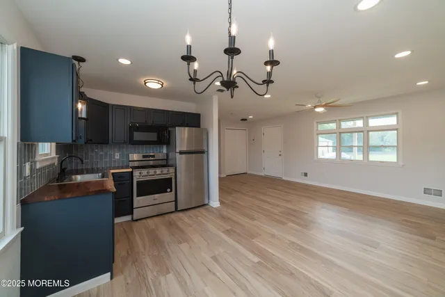 a kitchen with stainless steel appliances granite countertop a refrigerator a sink a stove and a cabinets