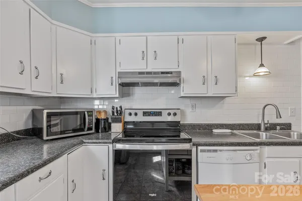 a kitchen with stainless steel appliances granite countertop a sink a stove and a white cabinets