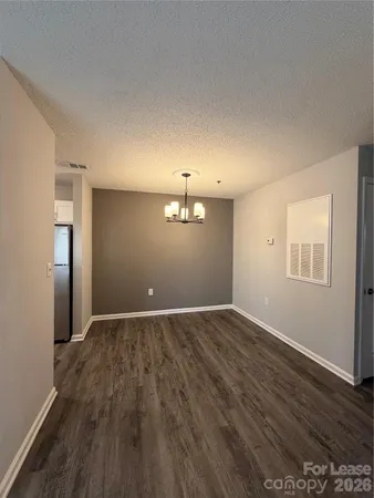 an empty room with wooden floor cabinet and windows