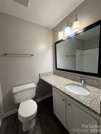a bathroom with a granite countertop toilet sink and mirror