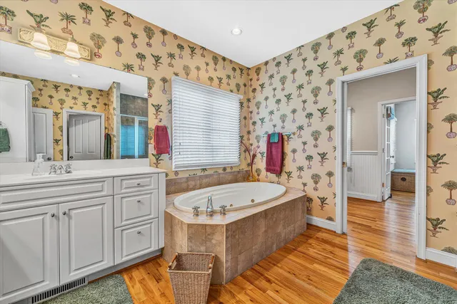 a spacious bathroom with a tub sink and mirror