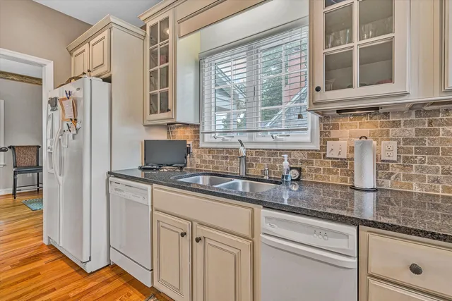 a kitchen with stainless steel appliances granite countertop a sink and a granite counter tops with wooden floors