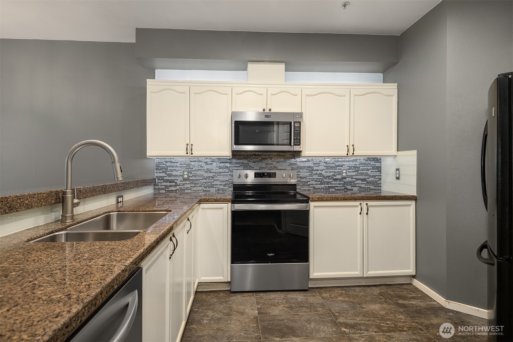 12113 Northeast 172nd Place, Unit J202 Bothell, WA 98011 - Photo 9 of 29 a kitchen with stainless steel appliances granite countertop a sink stove and refrigerator