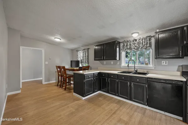 a kitchen with stainless steel appliances granite countertop a sink dishwasher a stove top oven a dining table and chairs with wooden floor